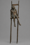 Bronze girl on chair sculpture on a mid-grey background