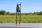 Bronze sculpture on a concrete table with a field and blue sky behind